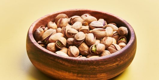 Bowl of pistachios over yellow background