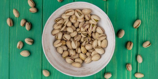 top view pistachios in a plate on a green background